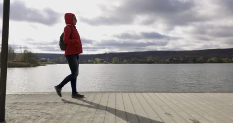 Young girl with a backpack, walking on the pier on the beach Stock Footage 143108751