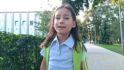 Young girl with backpack walking on sidewalk near trees Stock Footage 287588558