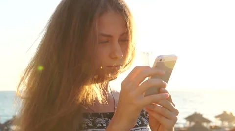 Young girl on the beach with your smartphone. Sunset Stock Footage