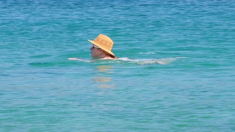 A young girl in a beige straw hat, mirrored sunglasses, swims in turquoise Stock Footage 124690953