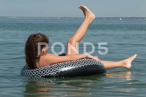 Young girl in a black buoy at the ocean Stock Photos