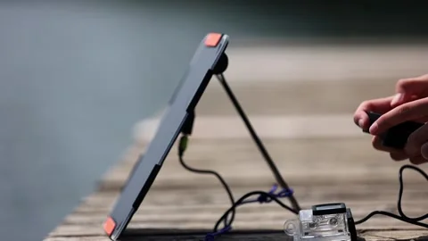 Young girl is checking camera charging status on a wooden pier. 스톡 동영상 157789294