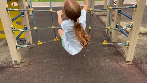 Young girl climbing on rope net frame in outdoor playground Stock Footage 166314160