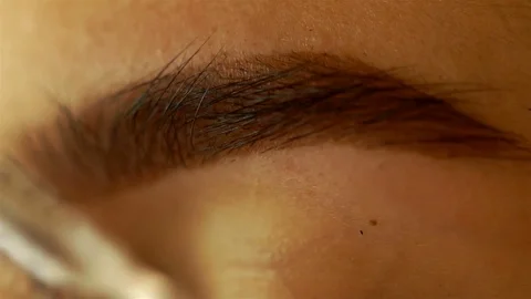 Young girl combing her thick eyebrows Stock Footage