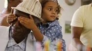 Young Girl Covering Her Grandfathers Eyes At His Birthday Party Stock Footage