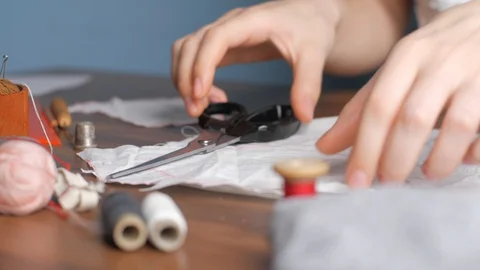 Young girl cuts out patterns with scissors for sewing a reusable protective m Stock-Footage 128363454