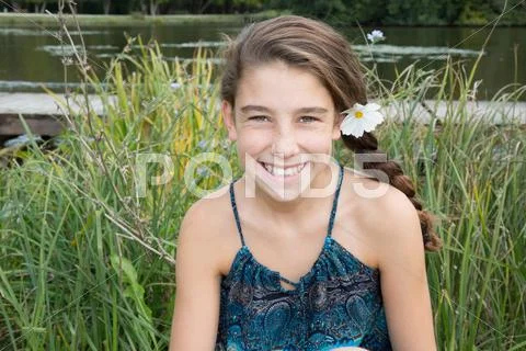 Young girl with a daisy in hair smiling at camera Stock Photos