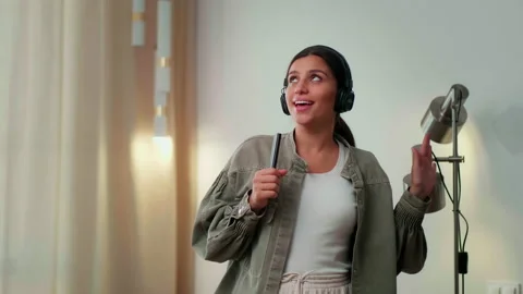 Young girl dancing and singing with a smile in headphones with a remote control Stock Footage 161069486