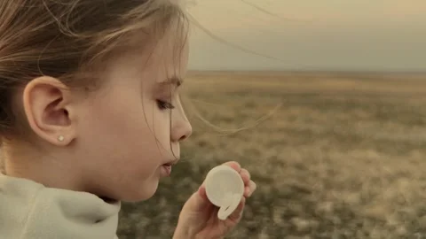 Young girl in deep thought, delicate hands holding an object, gazing into the Stock Footage 307773124