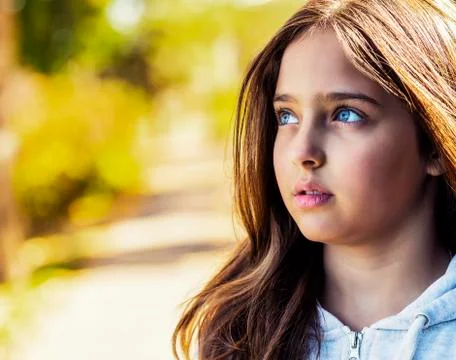 A young girl deep in thought while looking up on a warm autumn day in a city par 스톡 사진