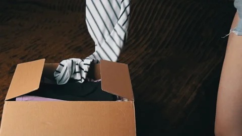 Young Girl Disassembles a Parcel With Things and Examines Clothes 動画素材 198310578