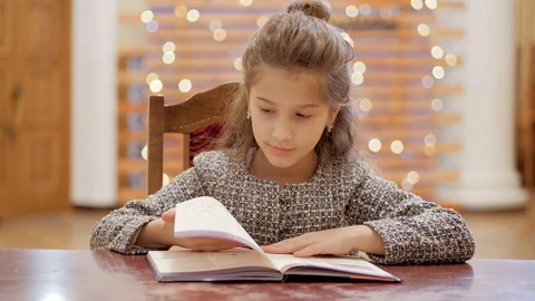 A young girl does homework, leafs through pages of a book. Stock Footage 120268415