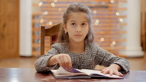 A young girl does homework, leafs through pages of a book.The girl is peeped out Stock Footage 120268534
