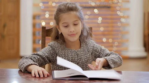 A young girl does homework, leafs through pages of a book. Stock Footage 120268594