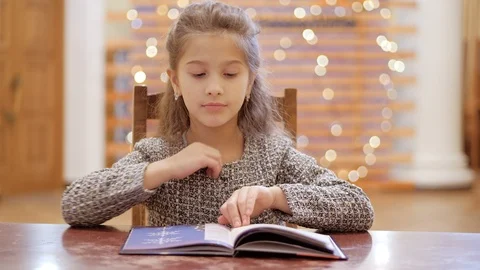 A young girl does homework, leafs through pages of a book.The girl is peeped out Stock Footage 120268751
