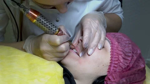 A young girl doing the procedure of permanent makeup lips in a beauty salon.  Video stock 98991304