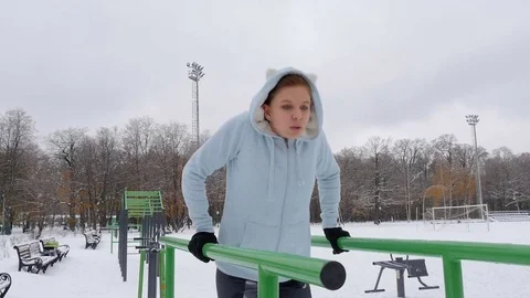 Young girl doing push-ups on the bars. Winter Stock Footage 69807822
