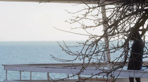 Young girl in down jacket walking on the balcoon on the beach in spring Video stock 62473582