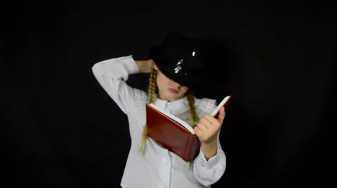 A young girl dressed in white writing in a diary pen on a black background Stock Footage 59448690