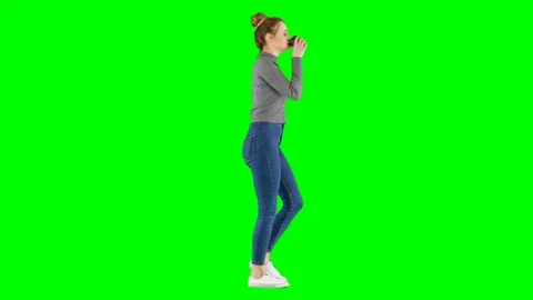 Young Girl Drinking Coffee While Walking on Green Screen Stock Footage 124617713