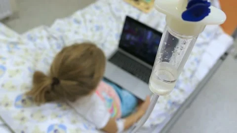 Young Girl on a Drip with Peripheral Venous Catheter Using Laptop in Hospital Stock Footage 143450153