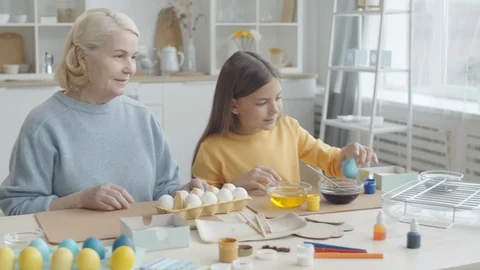 Young Girl Dying Easter Eggs with Grandmother at Home Stock Footage 124577380