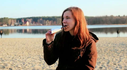 Young girl eats chocolate at river Stock Footage 61022982
