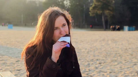 Young girl eats chocolate at river bank Stock Footage 61023015