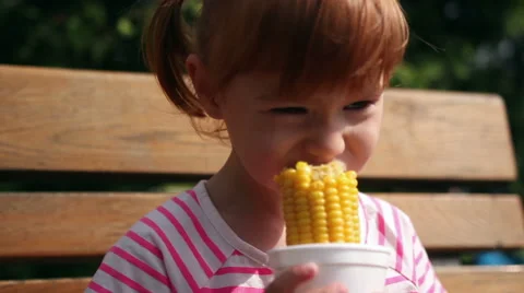 A young girl eats corn off of the cob 스톡 동영상 66460211