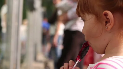 A young girl eats corn off of the cob and watching the animals at the zoo 스톡 동영상 66476243