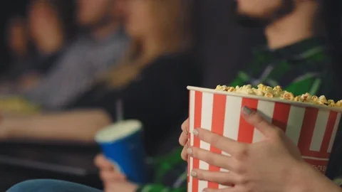 A young girl eats popcorn while watching a movie in a movie theater Stock Footage 95502444