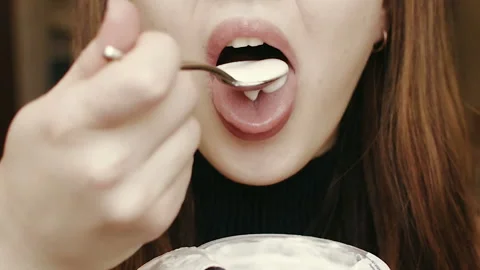 Young girl eats yogurt. Light breakfast. Close-up face. HD Vídeos de archivo 101660063