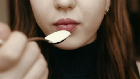 Young girl eats yogurt. Light breakfast. Close-up face. HD Stockbeeldmateriaal 101660704