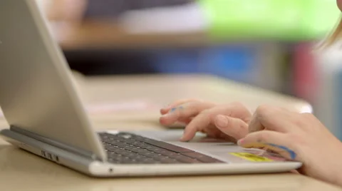 A young girl in elementary school types on a laptop computer. 動画素材 49220557