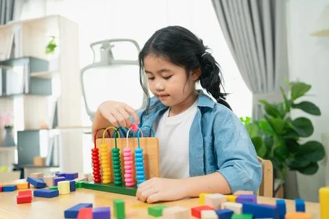 Young Girl Engaged in Learning Activity with Colorful Abacus and Building B.. Stock Photos