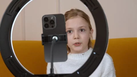 Young girl engaging with ring light during home recording 库存影片 315869517