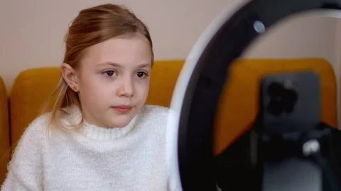 Young girl engaging with ring light during home recording 库存影片 315869958