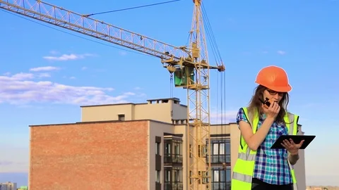 A young girl is an engineer on a construction site in a green vest and an ora Stock Footage 125285602
