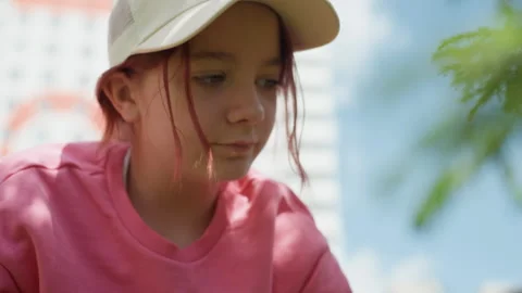 Young Girl Examining Small Object On Bench, Closeup Focus And Gentle Breeze Vídeos de archivo 327038539