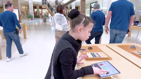 Young Girl Exploring New iPhone Models at an Apple Store Stock Footage 325081334