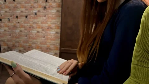 Young girl flips a page while reading a book in a university 動画素材 114293280