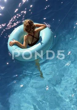Young Girl Floating In Pool In Inner Tube, Shot From Above.