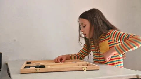 Young girl focused on playing a backgammon game indoors Stock Footage 290051293