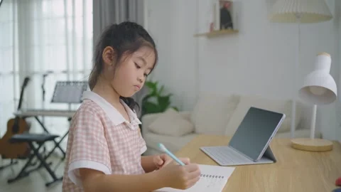 Young girl focused on writing notes in notebook while sitting at wooden tab.. Stock Footage 341459487