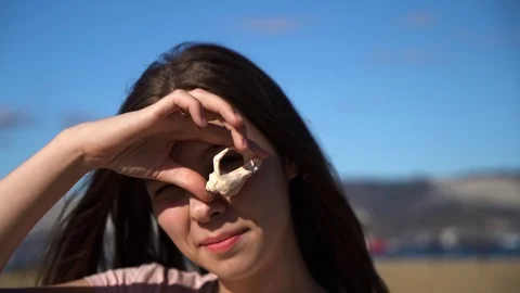 Young girl found shell on the beach and look in camera through it slow motion Stock Footage 116792267