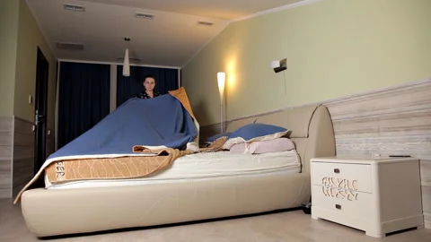 A young girl gets ready for bed, removes the bedspread from the bed and takes it Stock Footage 101205084