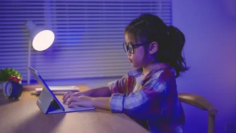 Young girl with glasses using digital tablet late at night in cozy room ill.. 動画素材 341459094