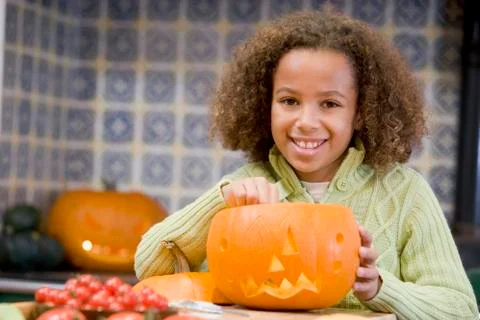 Young girl on Halloween with jack o lantern smiling Stock Photos