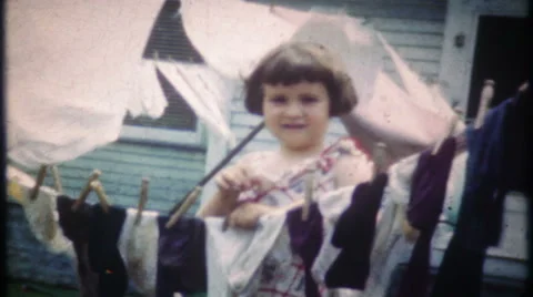 Young girl hangs laundry on clothesline 1950s vintage film home movie 3011 Stock Footage