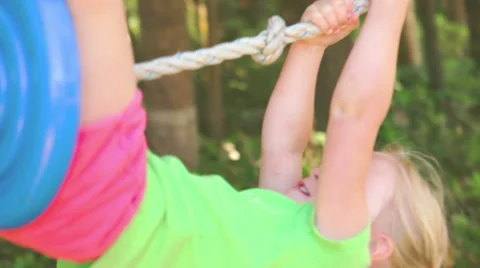 A young girl has fun while riding a swing hanging from a tress 库存影片 33873150